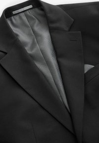 Schwarze Sakkojacke mit glatter Außenseite, ausgestattet mit einer geometrisch gemusterten grauen Futter, einer einzigen Brusttasche und dezenten Revers.