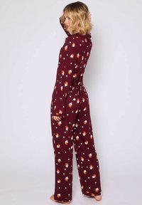 Conjunto de pijama color marrón burdeos con mangas largas y pantalones de corte amplio, que presenta un patrón de zorros naranjas y blancos y estrellas blancas sobre un fondo burdeos.