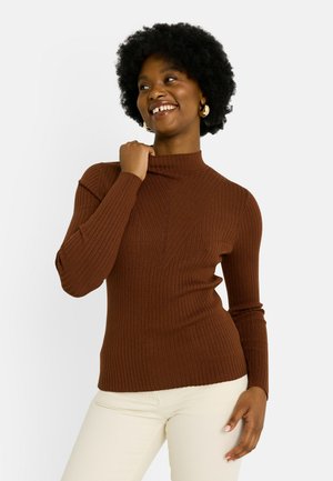 Suéter marrón de cuello alto de canalé con mangas largas, que presenta un patrón texturizado y un diseño ajustado. Combinado con pantalones de color crema.
