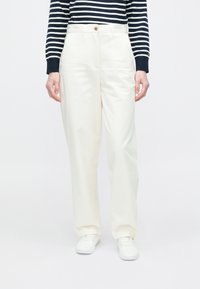 Hvite vide bukser med glatt finish, med knappelukking foran. Kombinert med en langermet topp med marineblå og hvite striper.