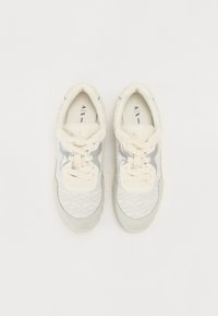 Lichtgrijze sneakers met een gestructureerde mesh bovenkant, crème veters en zilveren accenten aan de zijkant. Gevoerde zool voor comfort.
