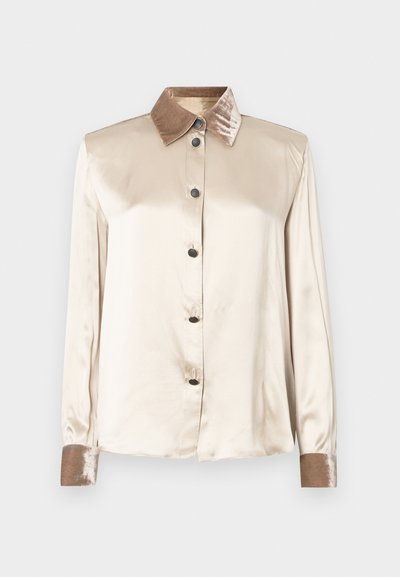 Kerman satiini-paita, jossa on samettinen ruskea kaulus, mustat napit edessä ja pitkät hihat, joissa on samettiset hihansuut.