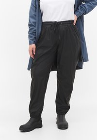 Pantalons noirs, légers et élastiques avec une taille à cordon de serrage. Caractéristiques des jambes fuselées et des poignets froncés, fabriqués à partir d'un matériau lisse et brillant.