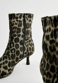Kotníkové boty s leopardím potiskem vyrobené z hladké látky, s bočním zipem a úzkým podpatkem. Barevná kombinace obsahuje odstíny hnědé a černé.