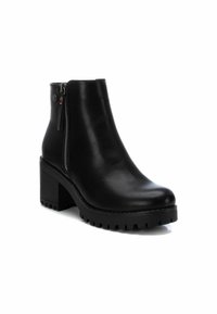 Botas de tobillo de cuero negro con cremallera lateral, tacón apilado, suela texturizada y acabado suave, con elementos de diseño minimalistas.