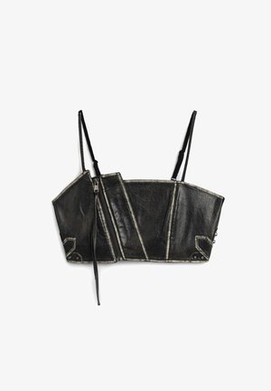 Top bustier noir court en matériau texturé avec des panneaux géométriques, détail de fermeture éclair et fines bretelles avec un surfil blanc contrastant.