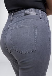 Grijze denim jeans met een hoge taille, achterzakken en een leren merkpatch met het label "Fox Factor" op de tailleband.