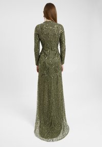 Lungo abito verde oliva con intricate perline e ricami. Presenta maniche lunghe e un corpetto aderente con orlo svasato. Chiusura con cerniera sul retro.