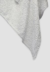 Tissu tricoté gris clair et doux avec une texture duveteuse drapé sur un fond blanc uni.