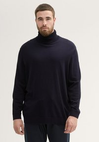 Suéter de cuello alto en azul marino oscuro con un ajuste relajado, mangas largas, cuello y puños de canalé, hecho de un material de punto suave.
