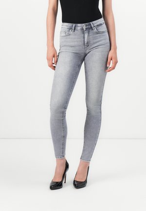 Gray denim skinny jeans with a high waist, featuring a subtle faded pattern and standard pockets. Paired with black patent high heels.