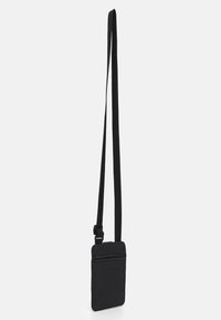 Black crossbody pouch made of textured fabric, rectangular shape, features a front zip pocket and an adjustable strap.