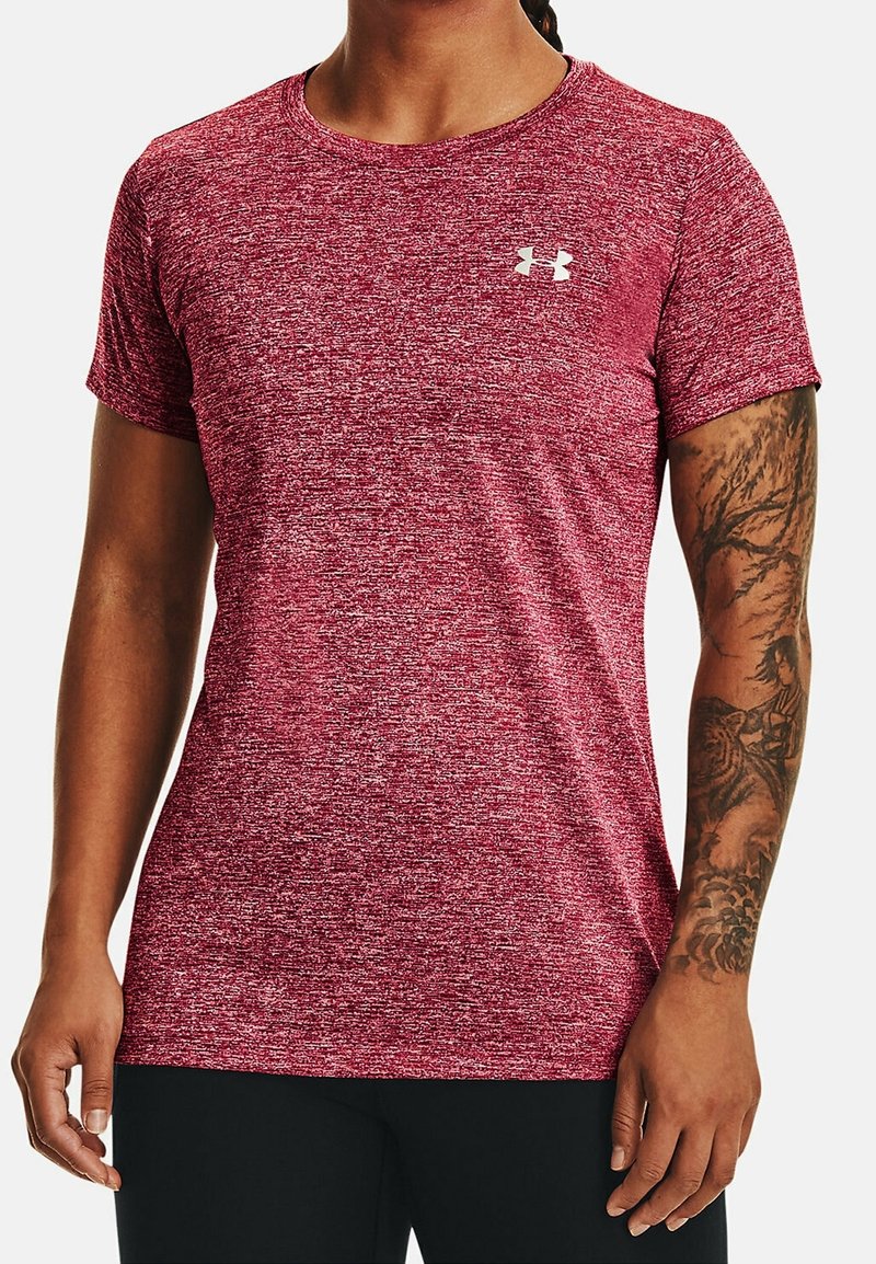 Person wearing marled red short-sleeve athletic shirt with white Under Armour logo, black pants, and a detailed tattoo on the right forearm.