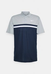 Polo tričko Nike s lehce šedým límcem a rukávy, námořnická modrá barva s bílým horizontálním pruhem přes hruď, krátké rukávy.