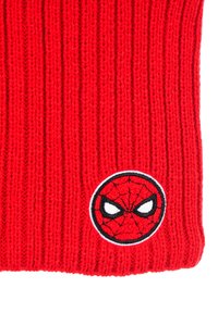 Rode gebreide beanie met verticale ribbels. Toon een ronde geborduurde Spider-Man-logo met zwart-witte accenten.