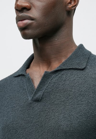 Σκούρο γκρι, υφασμένο πουλόβερ με απαλό φινίρισμα, με κλασικό γιακά και μερικώς ανοιχτή λαιμόκοψη, εμφανισμένο από το πλάι.