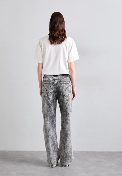 Grey denim flared jeans with a faded, distressed pattern, featuring back pockets and a black belt. Paired with a plain white T-shirt.