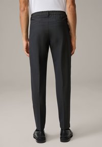 Black tailored trousers with a smooth texture, elastic waistband, and two rear pockets. The legs have a straight cut and subtle design.
