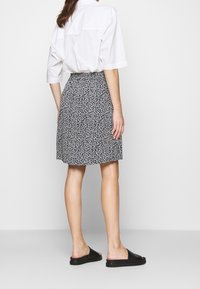 Kevyt kangas mustavalkoisessa kuviollisessa hameessa, jossa on liehkuva malli. Yhdistetty väljästi istuvaan valkoiseen paitaan ja mustiin liukusandaaleihin.