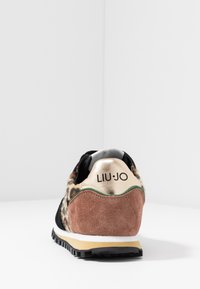 Sneakers med svart tygöverkänsla, leopardmönstrade accenter, rosafärgad mockahäl och guldlogotypdetalj på hälfliken. Svart yttersula.