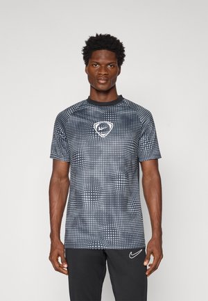 Cămașă sport scurtă cu mâneci, de culoare neagră și gri, cu un model cu puncte și un logo în formă de scut în centru. Fabricată dintr-un material neted și ușor.