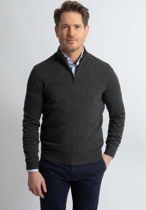 Dark gray zip-up sweater with a quarter-zip collar, ribbed cuffs, and a smooth texture, worn over a light blue collared shirt.