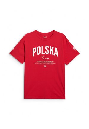 Młody mężczyzna w czerwonej koszulce z białym napisem „POLSKA Team” oraz motywującym przesłaniem wspierającym Reprezentację Polski.