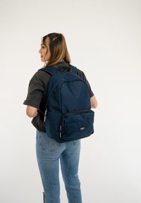 Navy blue backpack made of fabric with a smooth texture, featuring a large main compartment and a front zippered pocket.