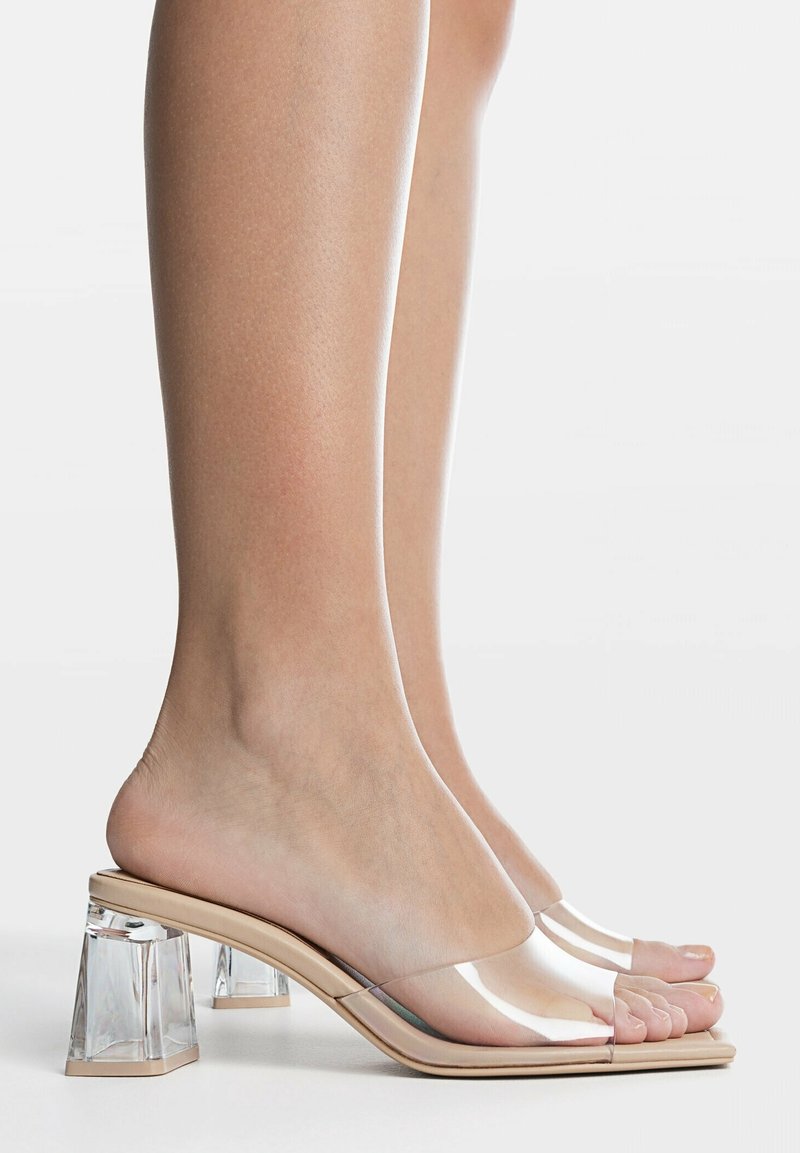 Sandales à talons transparents avec un bloc, talon en acrylique clair ; design à bout ouvert ; couleur nude avec une finition brillante ; forme épurée et minimaliste.
