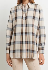 Camicia in cotone a quadri beige e blu con maniche lunghe, colletto abbottonato e una vestibilità rilassata. Presenta strisce verticali con colori a contrasto.