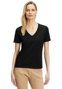 T-shirt nera a scollo a V realizzata in tessuto morbido con maniche corte, caratterizzata da un taglio classico e una texture liscia, abbinata a pantaloni beige.