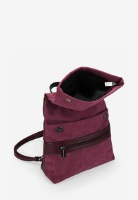 Mochila de cuero color burdeos con un acabado texturizado, cierre de solapa en la parte superior, bolsillo con cremallera en la parte frontal y correa de hombro ajustable. El interior parece negro.