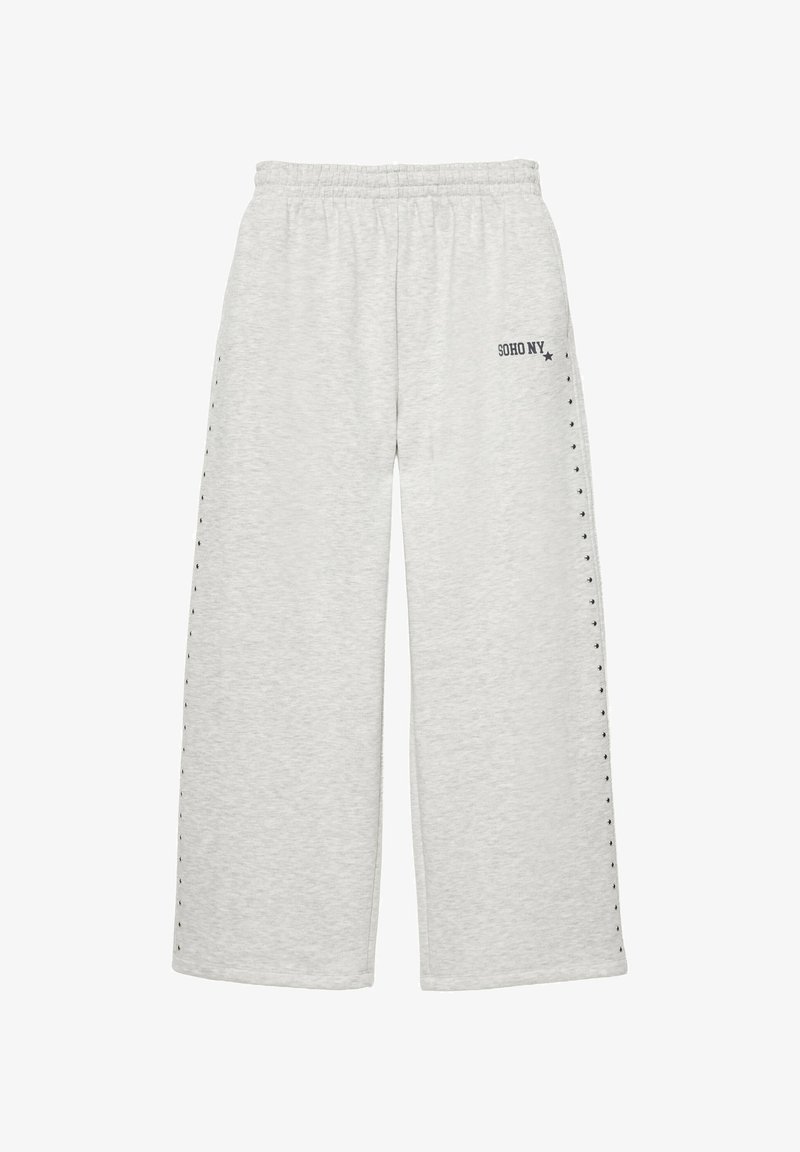 Pantalon de jogging gris clair à jambes larges avec ceinture élastique, petits clous noirs le long des côtés, et "SOHO NY" imprimé près de la poche gauche.