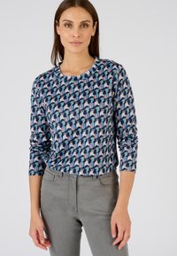 Patroon met lange mouwen in marineblauw met geometrische vormen in lichtblauw, roze en creme. Ronde hals, zachte stof, slim-fit stijl. Gestyled met grijze broek.