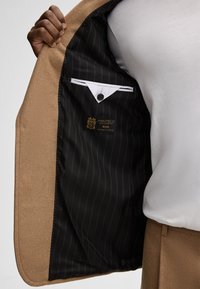 Braune Wolljacke mit schwarzem Nadelstreifenfutter, Innentasche und Manteco-Label. Knopfverschluss im Inneren.