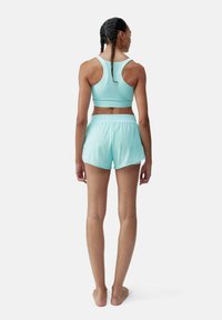 Lichtblauwe sportbeha en bijpassende shorts, gemaakt van glad, rekbaar materiaal. De beha heeft een racerback ontwerp; de shorts hebben een elastische tailleband.
