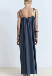 Rochie maxi fără mâneci, de culoare albastru închis, cu spate plisat, bretele reglabile și un design fluid, realizată dintr-un material moale și elastic.