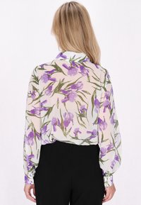 Bluz�ă transparentă cu un model floral, având irisuri mov pe un fundal deschis, cu mâneci lungi și manșete cu nasturi. Țesătură ușoară.