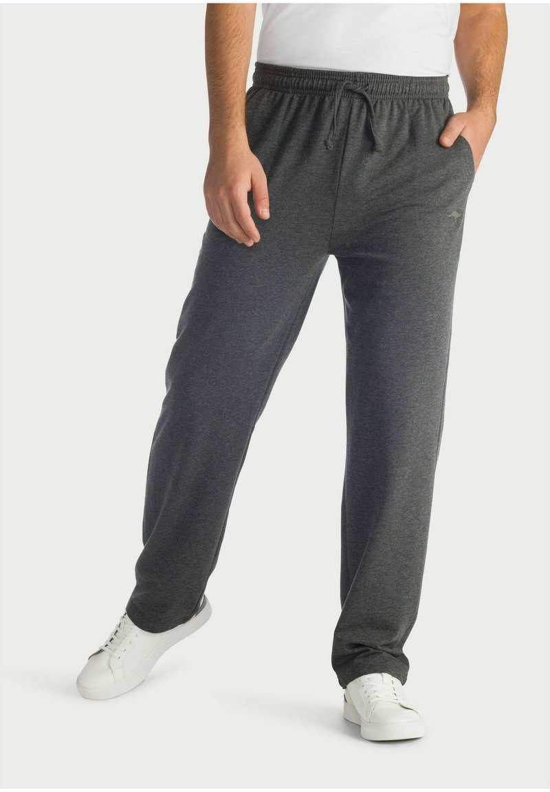 Graue Fleece-Loungehosen mit einem elastischen Bund und Kordelzug, ausgestattet mit Seitentaschen und einem lockeren Schnitt, kombiniert mit weißen Turnschuhen.