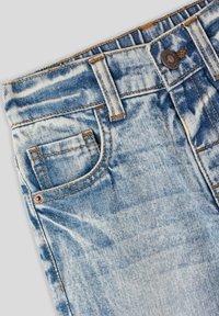 Jeans in denim blu sbiadito con vita media, dotati di una piccola tasca frontale, chiusura con bottone metallico e dettagli di cucitura a contrasto.