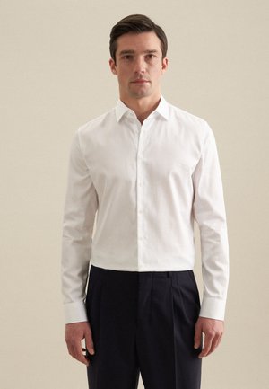White button-up shirt with a classic collar, made of woven cotton. Long sleeves, button placket, and a fitted design.