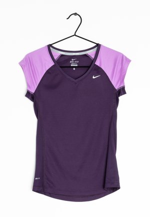 Camiseta de manga corta Nike Dri-FIT en tonos morado y lavanda con cuello en V colgada en una percha negra sobre un fondo blanco.