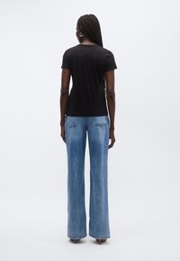 Svart t-skjorte med korte ermer kombinert med vide, lyseblå jeans, med en klassisk passform og rene sømmer.