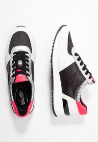 Sneakers med en svart nätövre del, silverdetaljer och rosa inslag. Sulan är vit med texturerat svart gummi.