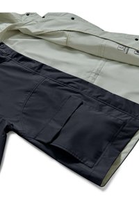Vandafvisende jakke med et lyst grått ydre lag og mørkeblå inderside, udstyret med trykknapper, en foldbar krave og en sidelomme.