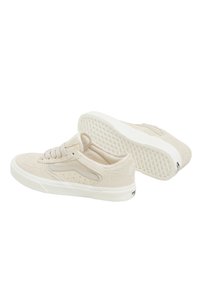 Beige mockasins i låg design, med vita gummisulor och subtila perforeringar på sidorna. Snörning och en dragflik på hälen.