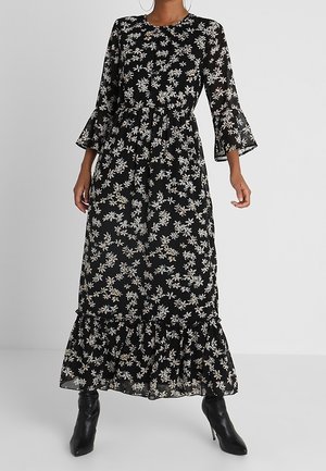 Vestido largo negro con un patrón floral, tela transparente, mangas acampanadas y un dobladillo con volantes. Presenta un cuello redondo y una cintura ceñida.