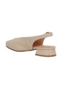 Zapato slingback beige con punta redondeada, parte superior de cuero suave y tacón bajo en bloque. Diseño de cortes destaca en los laterales y en la parte trasera.