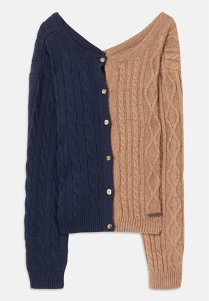 Two-tone cardigan featuring navy on one side and light brown on the other. Cable knit design with buttons along the navy side.