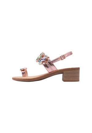 Sandalo in oro rosa con finiture metalliche, dettagli decorativi in gioielli, una cinturino regolabile e un tacco a blocco moderato. Suola piatta con motivo testurizzato.